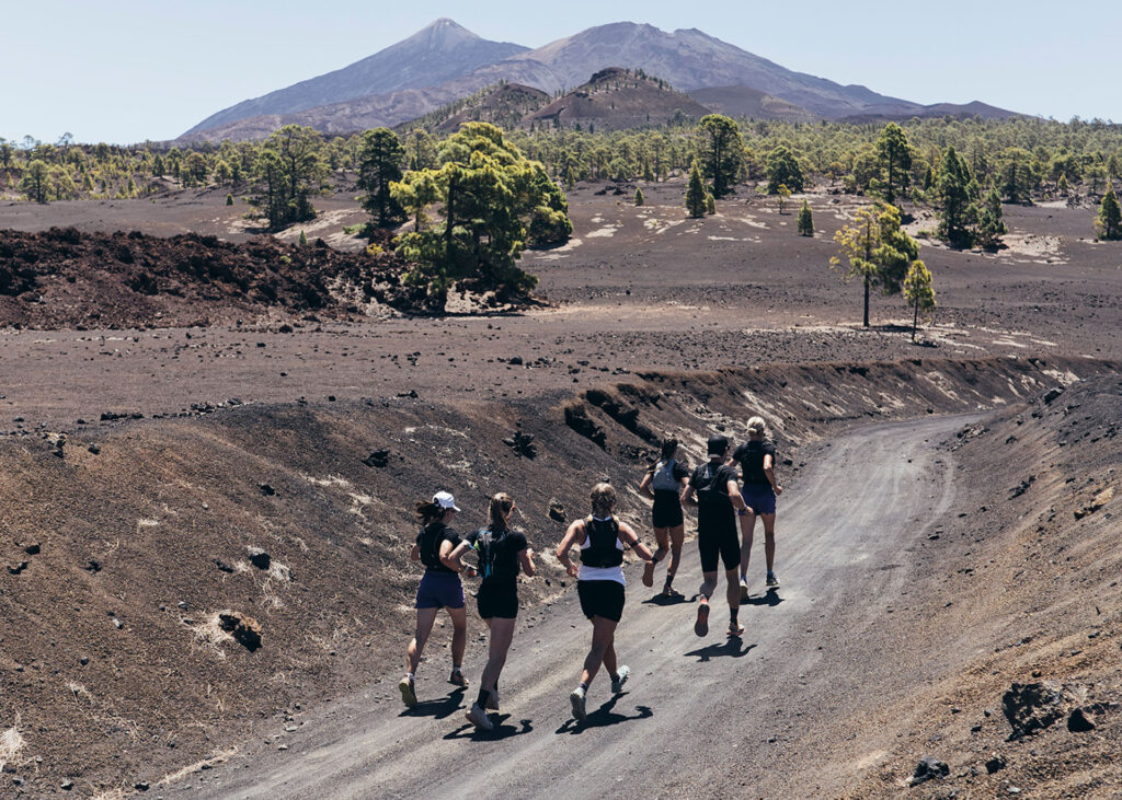 Gruppe von Läufern auf einer Vulkanstraße mit dem Teide im Hintergrund.