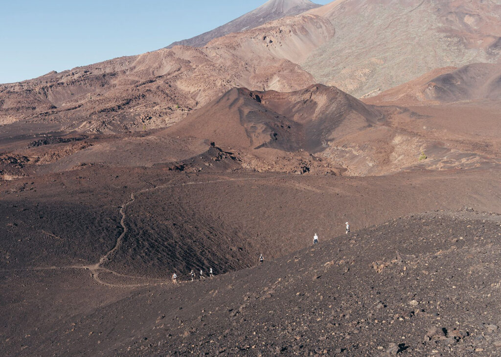 Wanderer auf einem Pfad durch die karge Vulkanlandschaft des Teide auf Teneriffa.