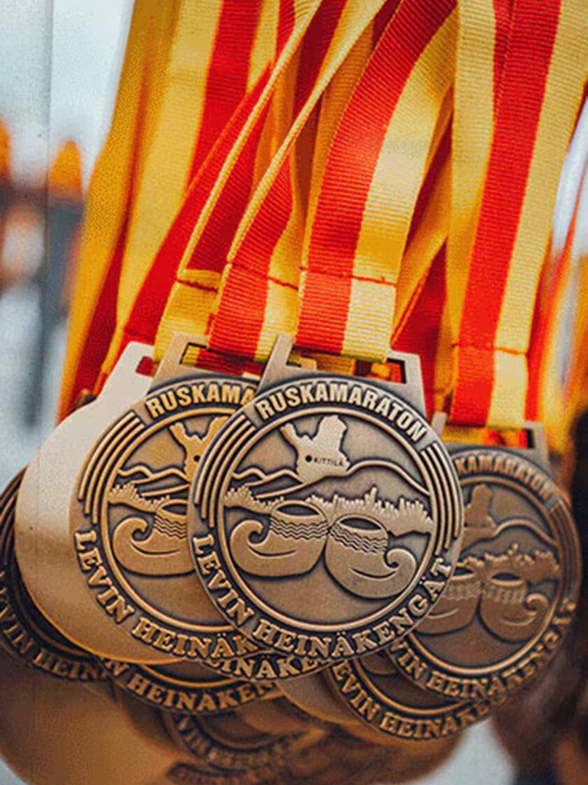 Medaille des Ruskamaraton mit rot-gelben Bändern und stilisiertem Logo.