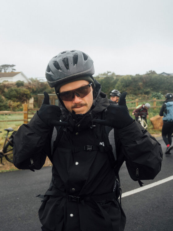 Radfahrer mit Helm und Sonnenbrille zeigt Handzeichen.