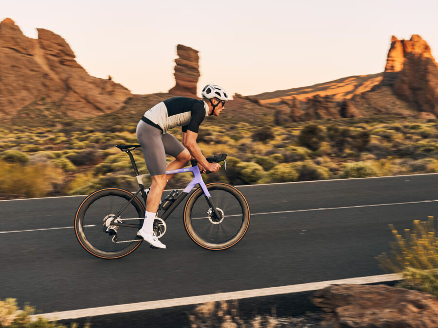 Radfahrer auf einer Straße in einer malerischen Wüstenlandschaft bei Sonnenuntergang.