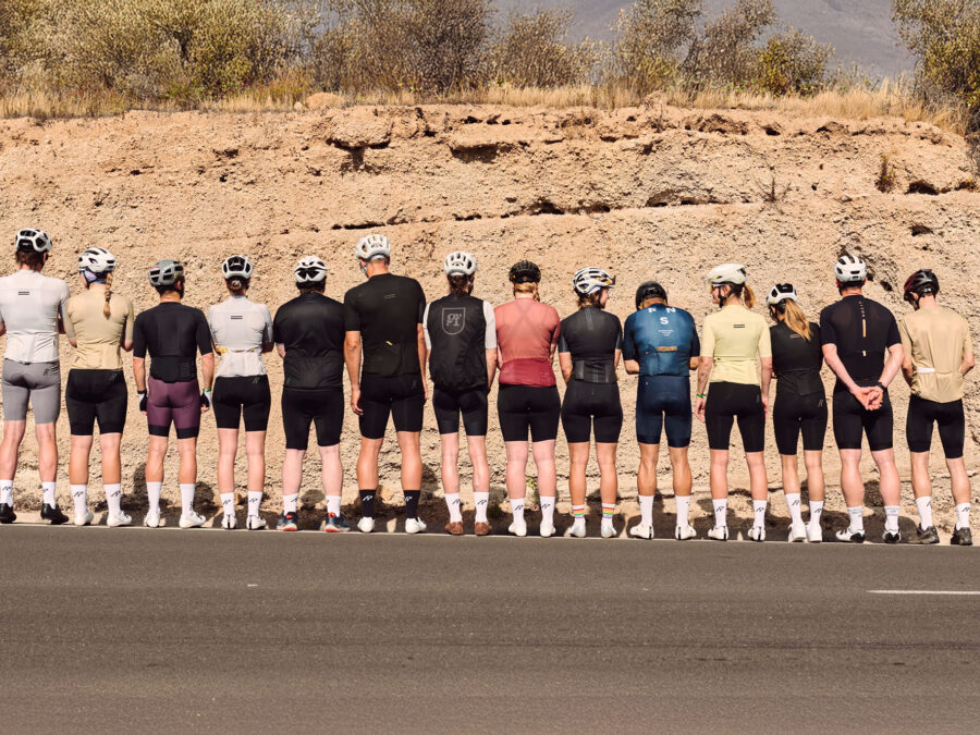 Gruppe von Radfahrern in Sportkleidung, die an einer Straße steht.