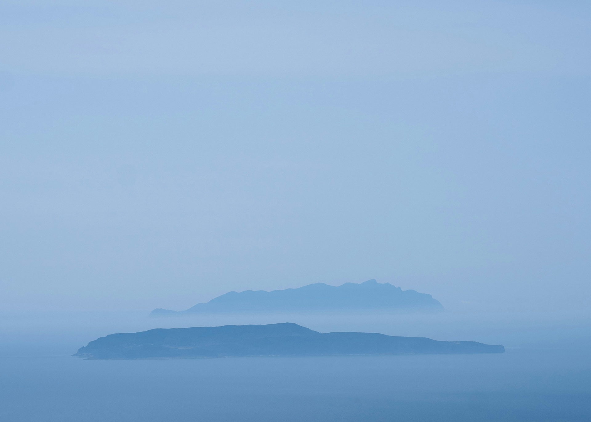 Blaue Inseln im Nebel über ruhigem Wasser, ideal für Reisefotografie und Naturerlebnisse.