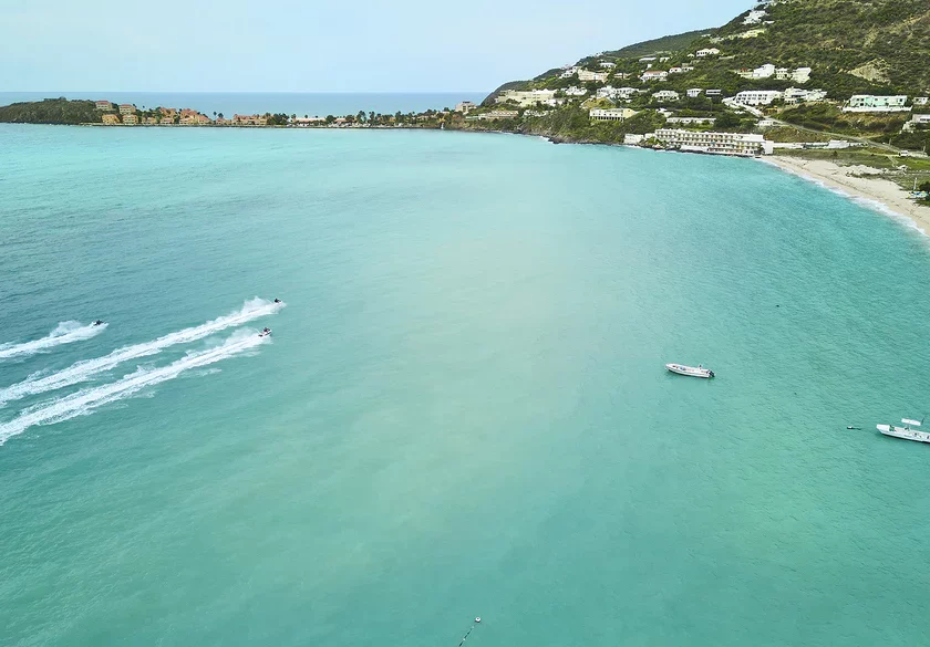 Blick auf eine malerische Küste mit Booten und türkisfarbenem Wasser.