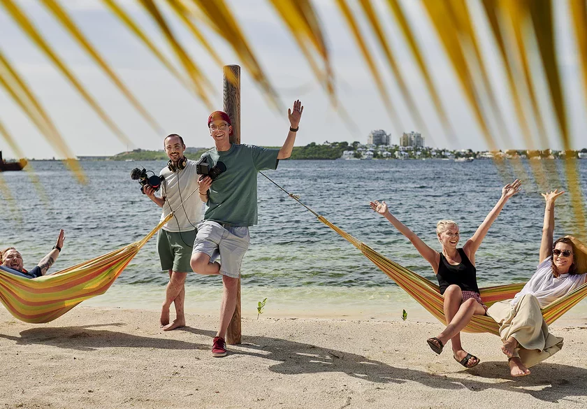 Freunde entspannen in Hängematten am Strand und genießen die Sonne.