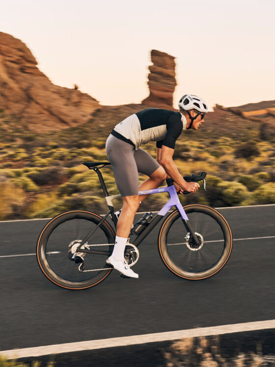 Sportlicher Radfahrer auf einer Straße in einer malerischen Landschaft bei Sonnenuntergang.