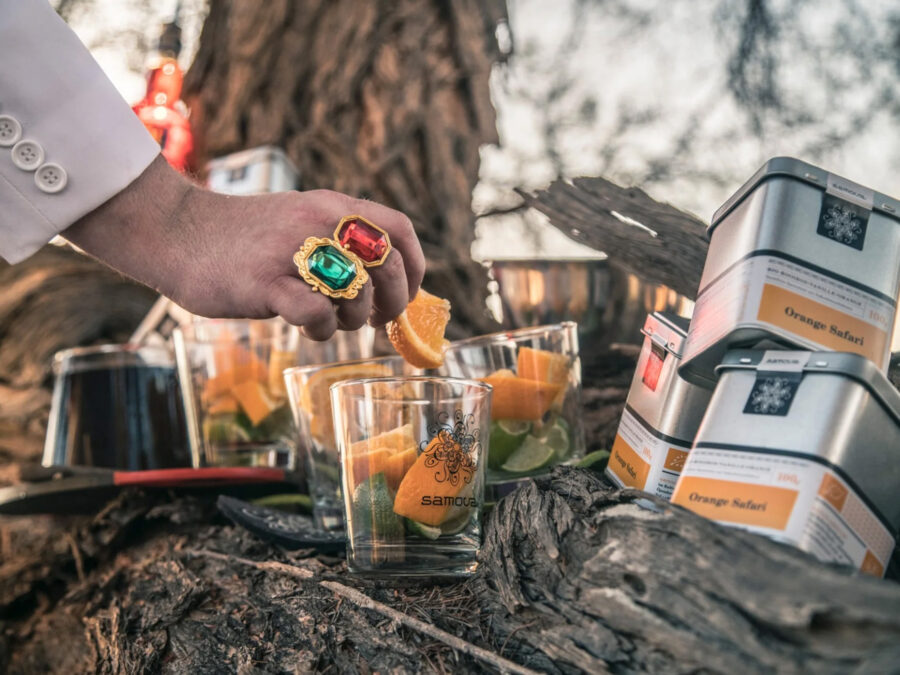 Eleganter Drink mit frischen Orangenstücken und Teedosen in natürlicher Umgebung.